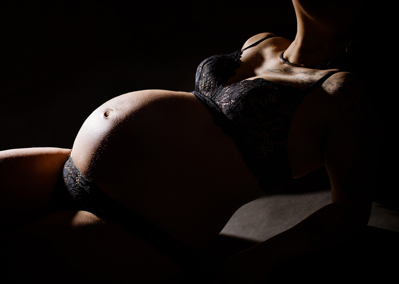 Babybauch auf dunklem Hintergrund
