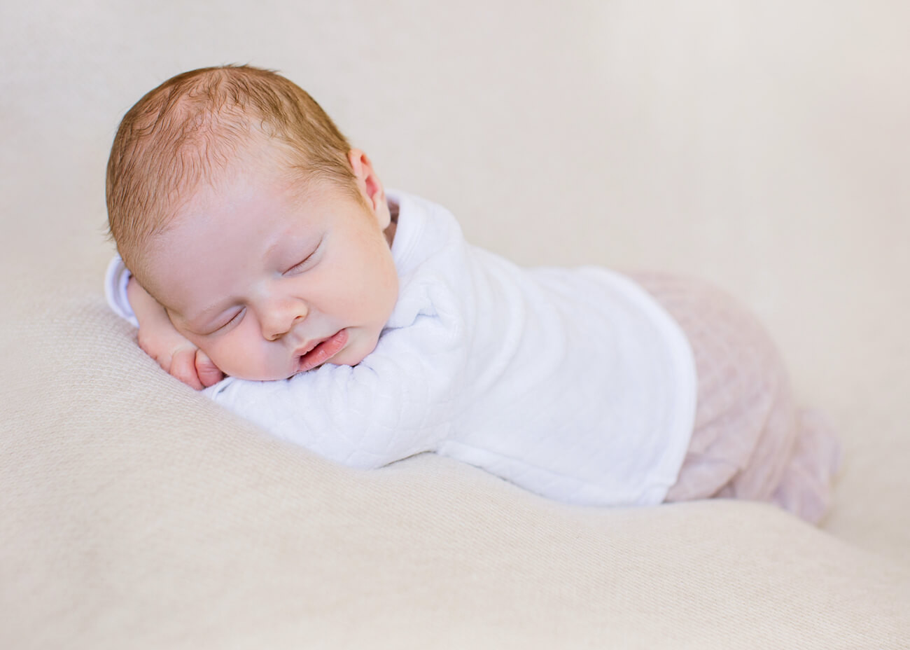 auf Bauch schlafendes Baby im weißen Body