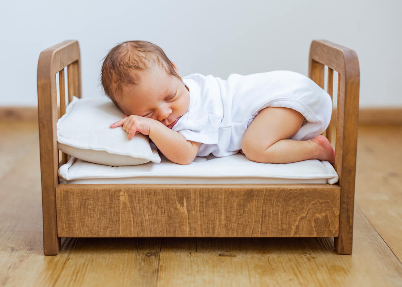 Baby auf Bauch liegend im Bettchen, Babyfotograf Erzgebirge