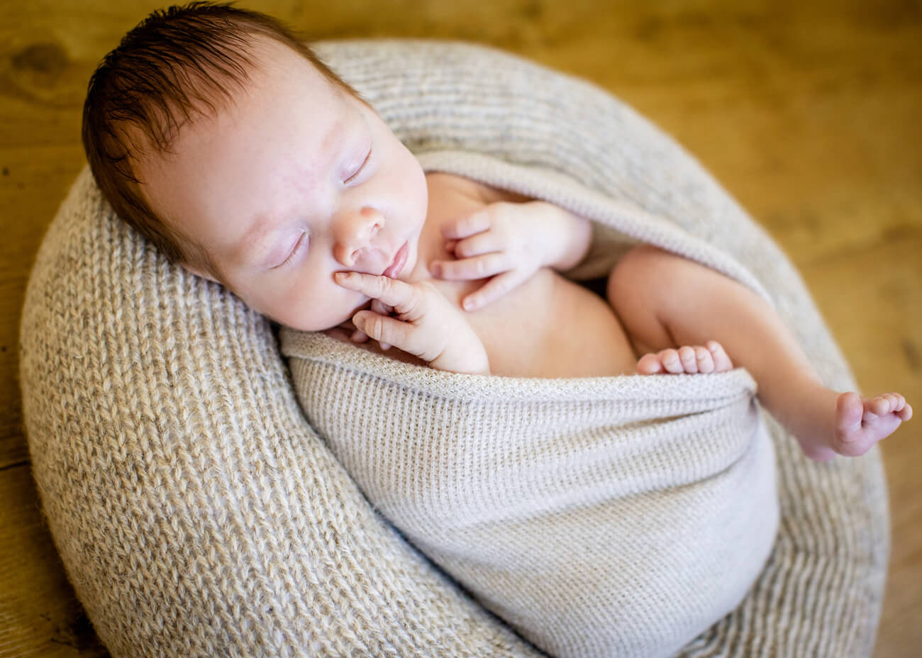 schlafendes Baby im Nest und Finger am Mund, Babyfotos Erzgebrige