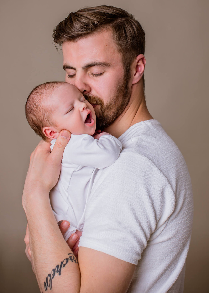 Papa küsst Baby auf Arm