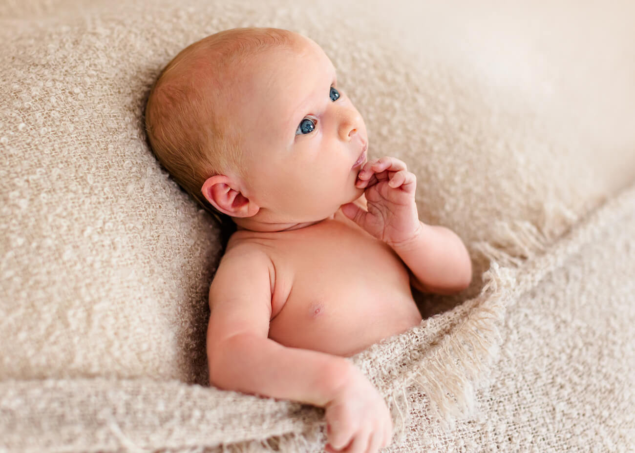 Baby mit Hand am Mund in die Höhe schauend