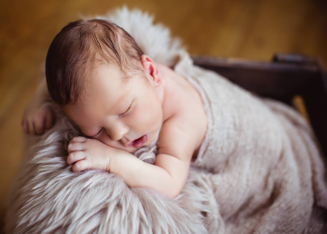 schlafendes Baby in Holzkiste mit Kopf auf Felldecke, Babyfotos Erzgebirge