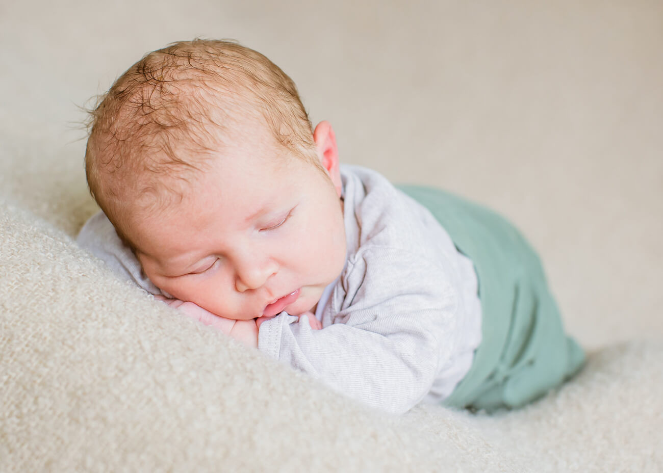 Baby schläft auf Bauch mit grüner Hose