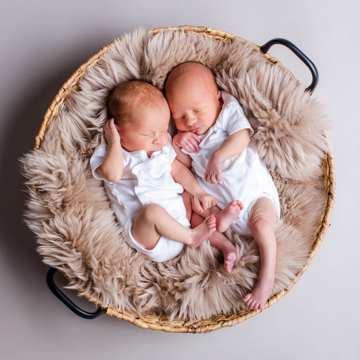 Zwillingsbabys in rundem Korb auf Felldecke